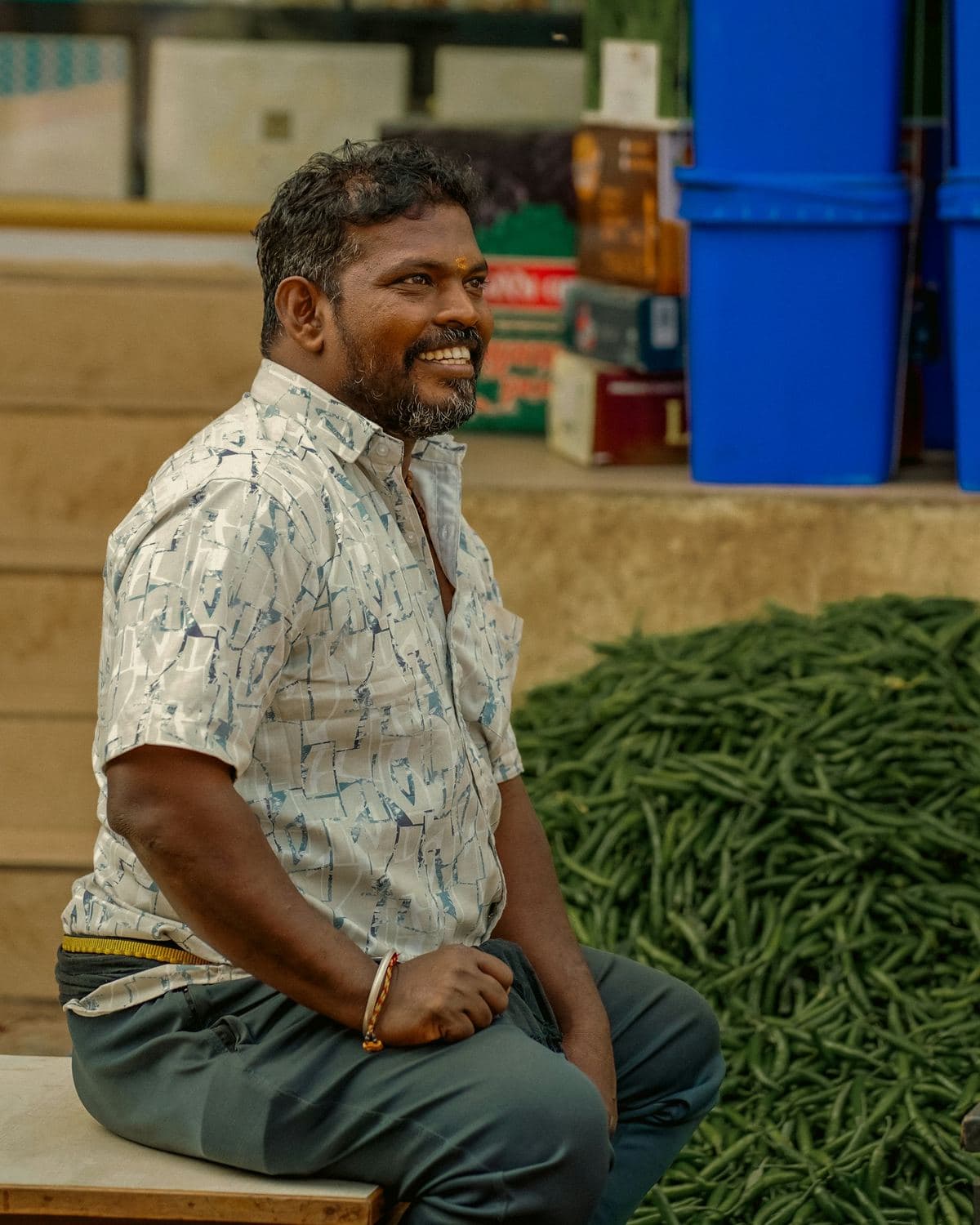 A trader at a mandi beside a pile of fresh beans